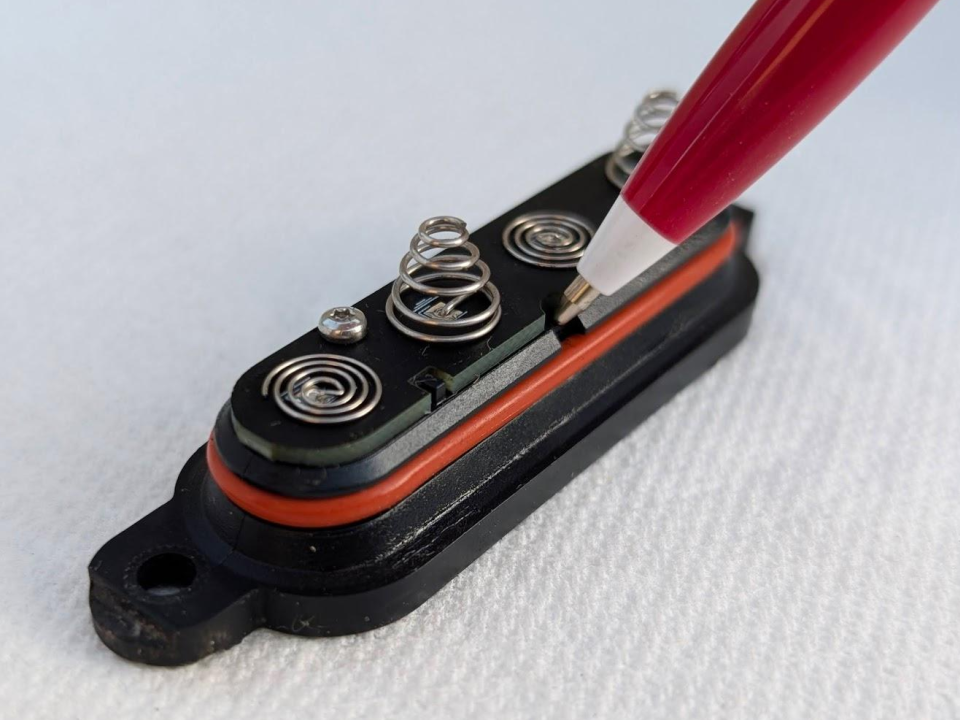 Using a dull pen to gently remove rubber O-ring out of its grrove on battery cap (1 of 2)