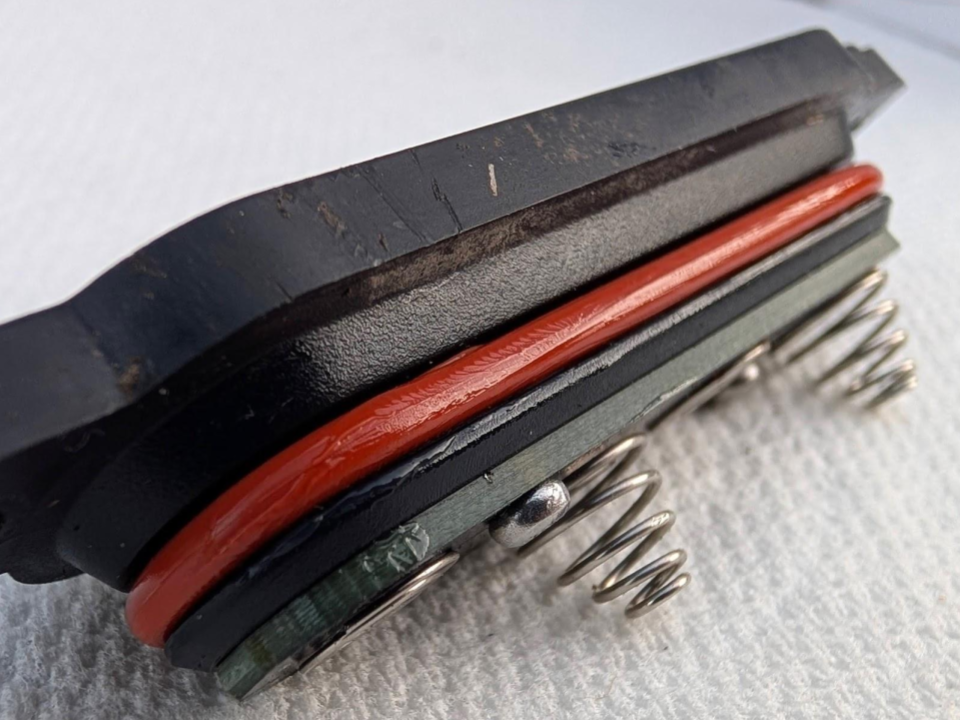 A detailed close-up of the lubricated O-ring fully and correctly seated within its groove on the battery cap, showing a subtle, uniform glossy sheen indicative of the perfect grease amount for a secure seal